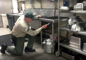 Dugas Pest Control exterminator performing a commercial kitchen pest treatment